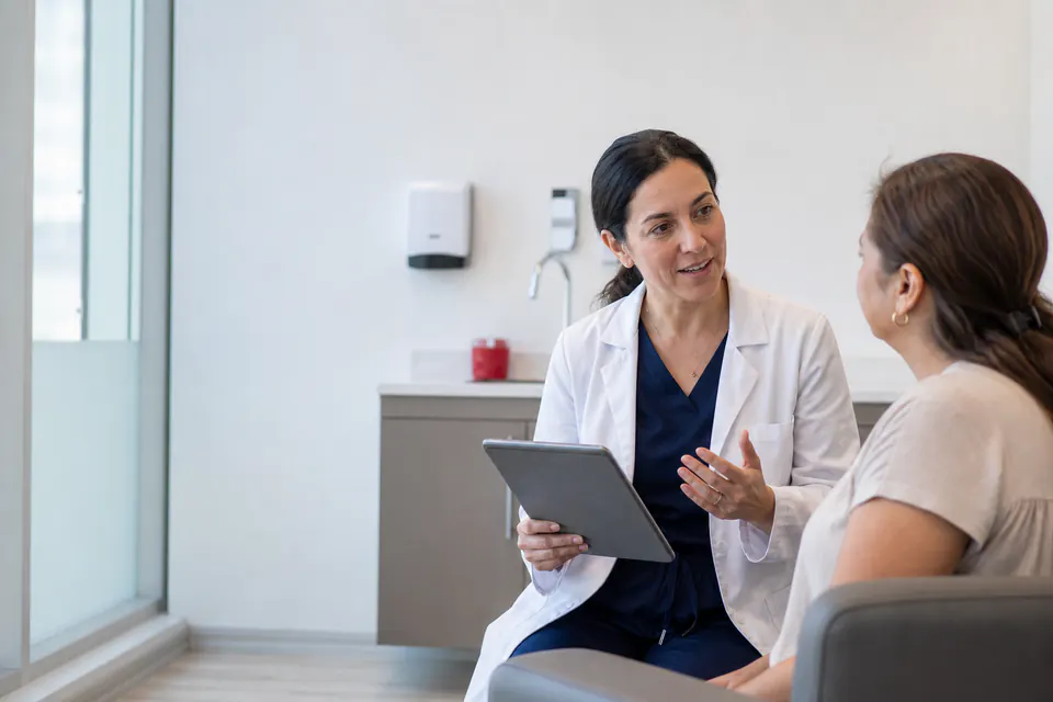 Médico conversando con una paciente en una consulta luminosa